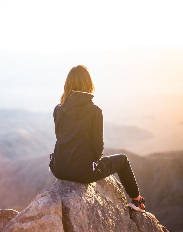 A picture of a woman sitting on a mountain top